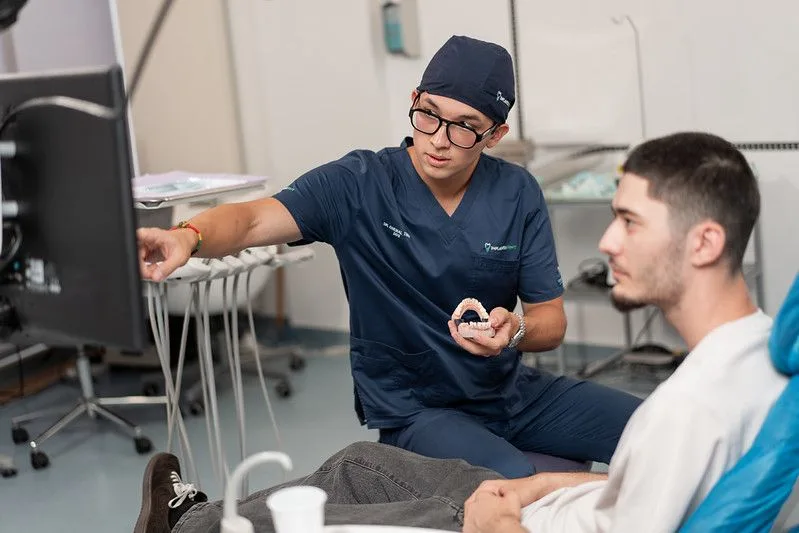 Medic Implantodent explică pacientului planul de tratament pe un model de arcadă