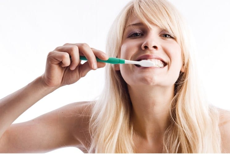 Femeie care se spală pe dinți, ilustrând îngrijirea gingiilor