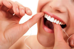 Pacientă care folosește ața dentară între dinții din față