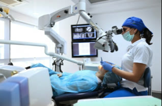 Medic parodontolog lucrând la microscopul dentar, într-un cabinet Implantodent