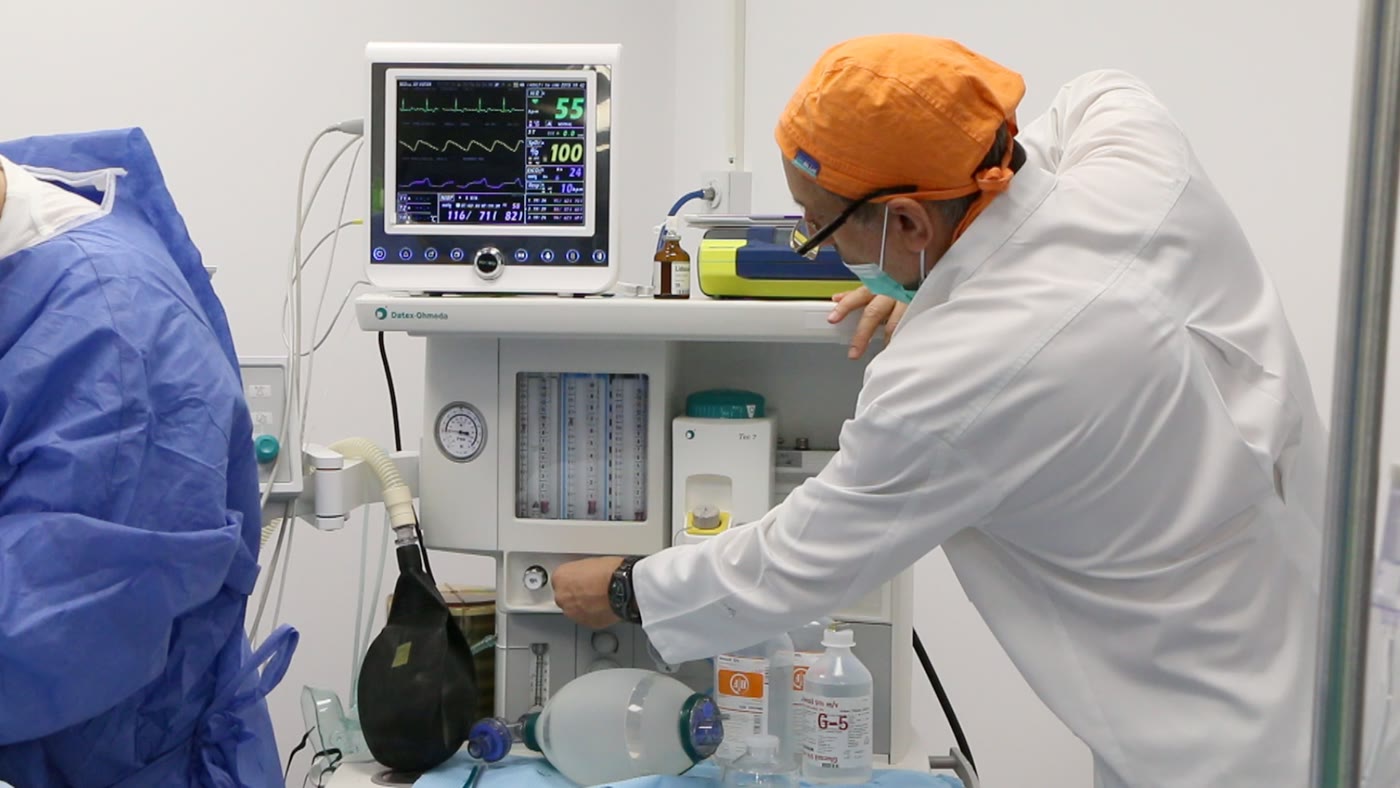 Blocul operator al clinicii: aparatul de anestezie și monitorul funcțiilor vitale, cu medicul anestezist lângă pacientul acoperit cu câmpuri sterile