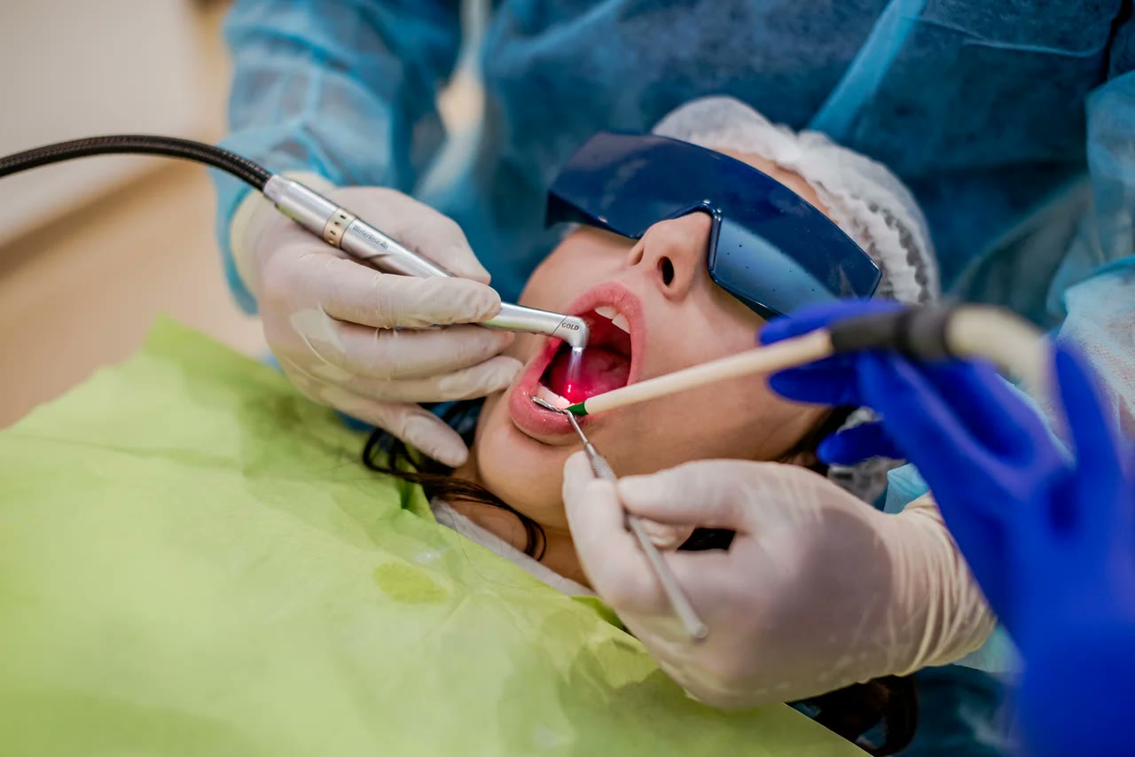 Tratament dentar cu laser realizat intraoral, cu pacienta protejată cu ochelari speciali