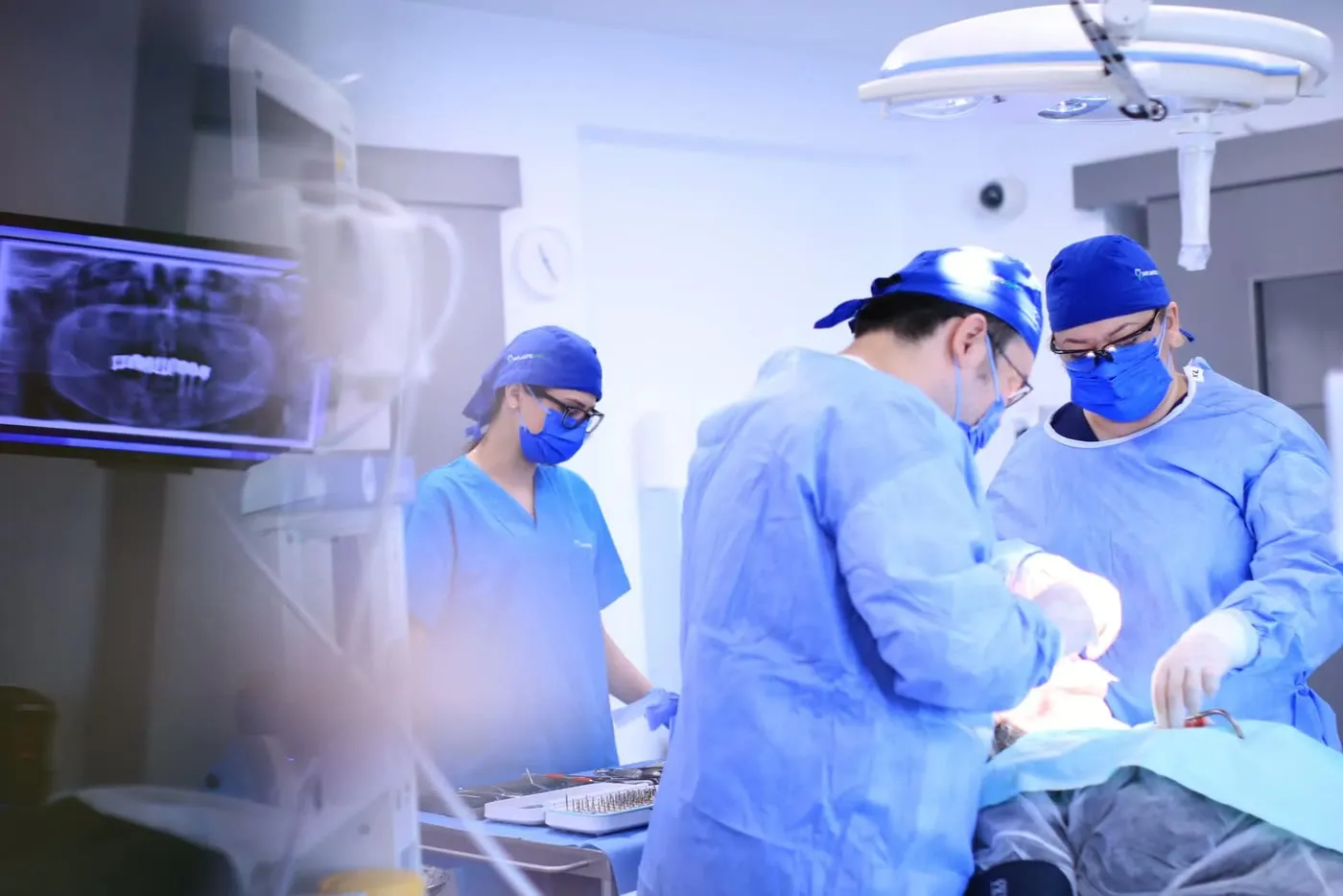 Echipa Implantodent în blocul operator, cu radiografia panoramică a pacientului afișată pe monitor