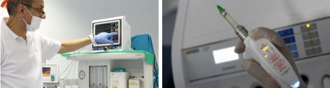 Medicul specialist ATI verificând monitorul de funcții vitale și seringa de sedare conectată la injectomat