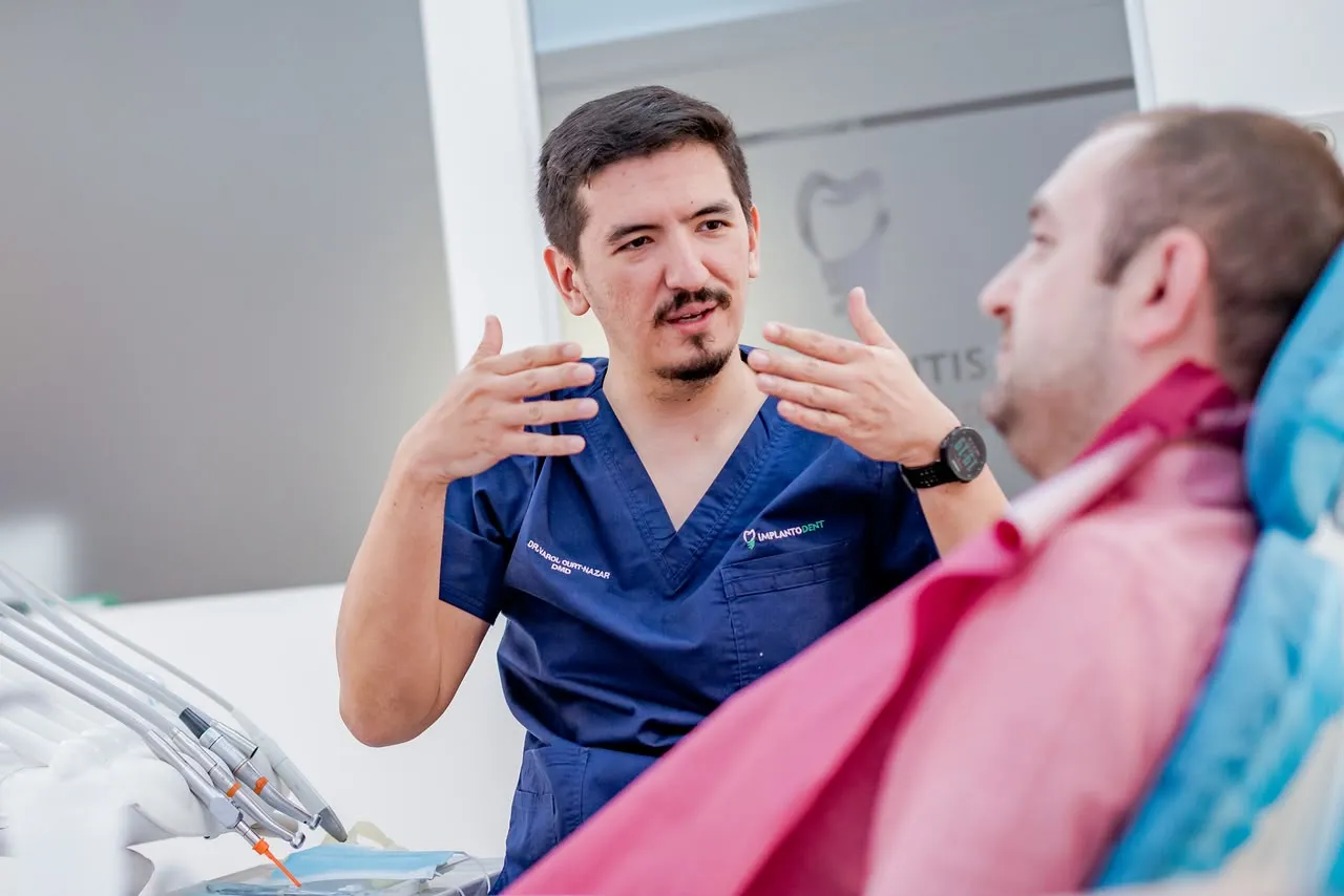 Medic Implantodent discută cu un pacient în cabinet, înainte de tratament