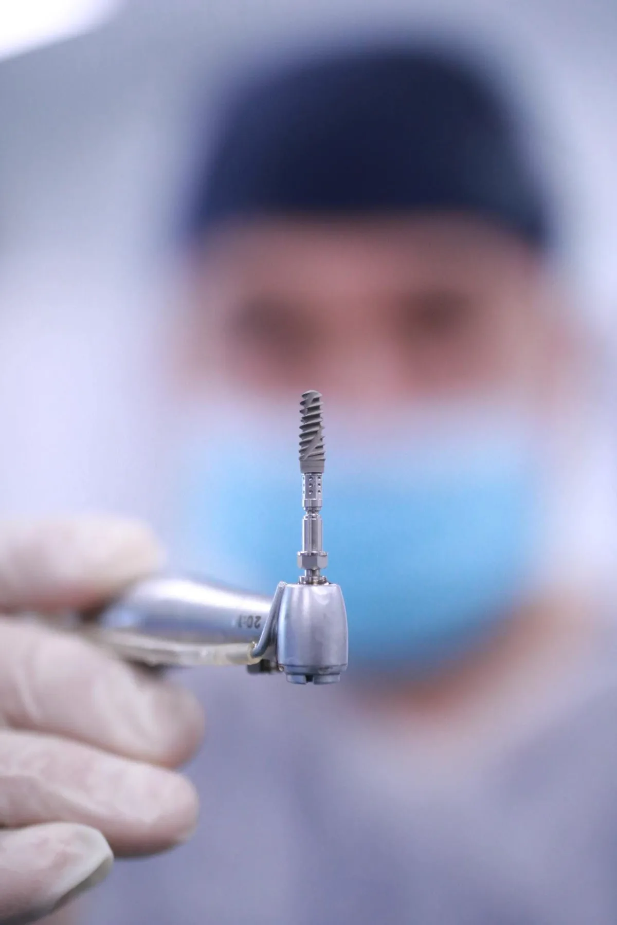 Implant dentar din titan, prins în piesa de inserare, înainte de a fi montat