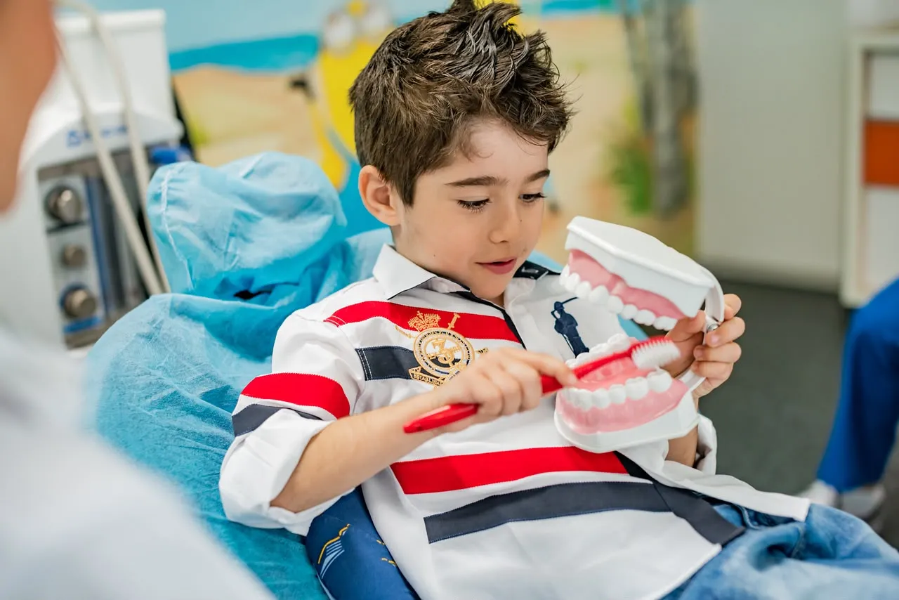 Copil în cabinetul Implantodent Junior, învățând să se spele pe dinți pe un model de arcadă dentară