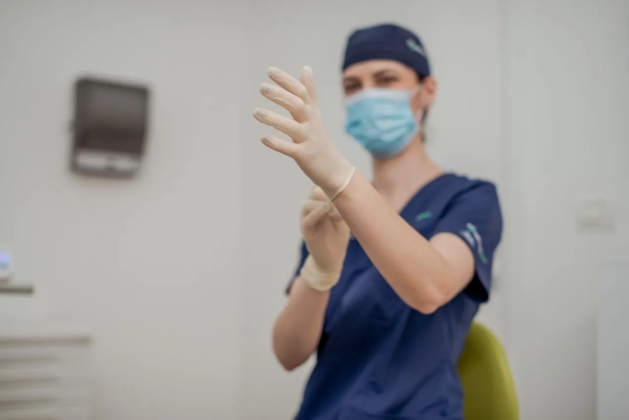 Medic Implantodent își pune mănușile sterile, înaintea intervenției